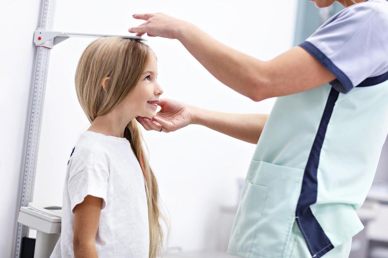 Female doctor measuring height of girl in clinic
