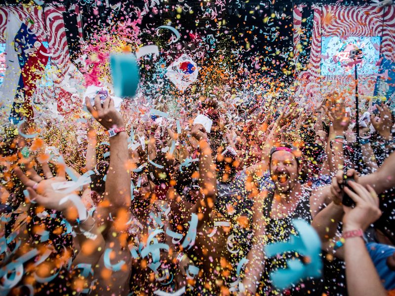 Festival goers throw confetti at each other at 24th Sziget Festival
