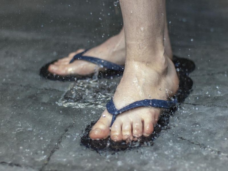 Flip flops on the feet of a person in the shower