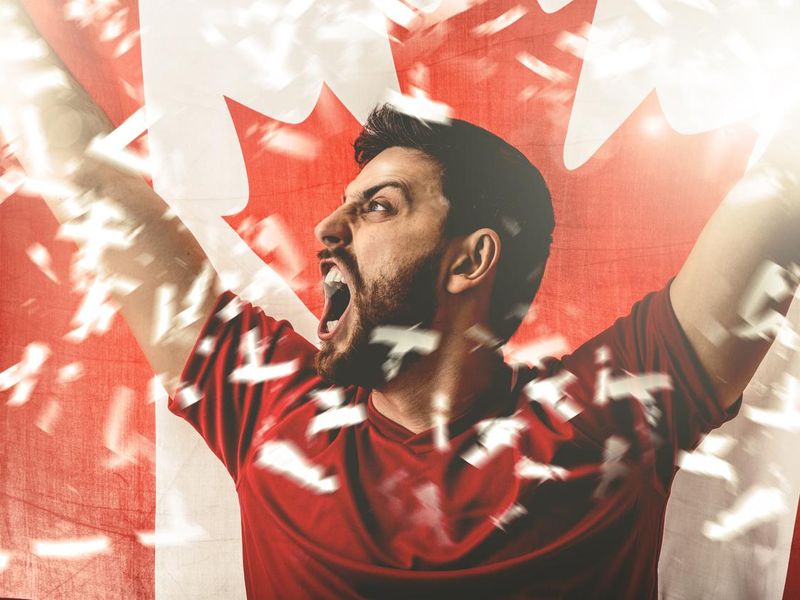 Football fan celebrating and holding the flag of Canada
