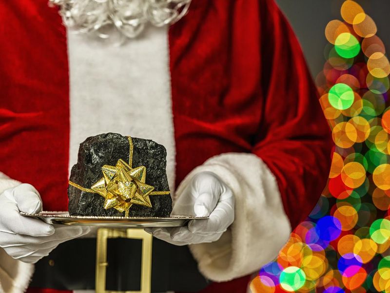 Funny christmas gift of Santa Claus holding lump of coal