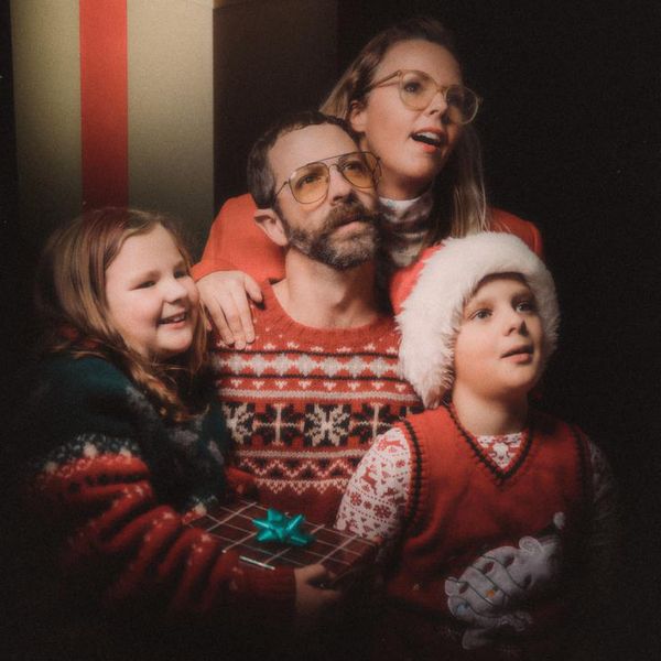 An awkward retro styled image of a family getting a studio portrait for the holiday season, wearing ugly Christmas sweaters and daydreaming of their gifts.