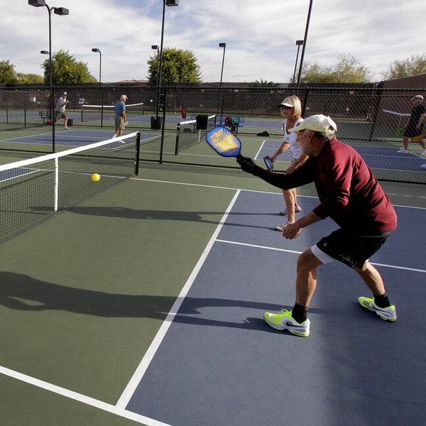 In this Monday, Dec. 3, 2012 photo, clockwise from left; Gary Dyson, Del Teter, Donna Shattenberg and David Bone compete in a game of pickleball at Sun City West senior community in Surprise, Ariz. A hybrid of tennis, badminton and table tennis, pickleball is played on a court a quarter the size of a tennis court, with hard rackets and a variety of whiffle ball. "It's really easy to learn, it's a lot of fun and it's a very social game because you're in a small area with a lot of interaction," said Bill Booth, president of the USA Pickleball Association.  (AP Photo/Matt York)