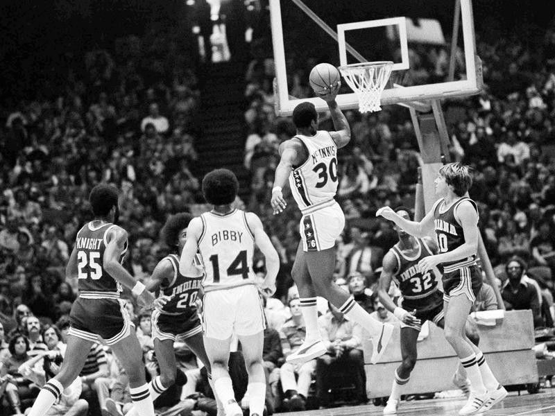 George McGinnis goes by Indiana Pacer's Don Buse for one-handed shot