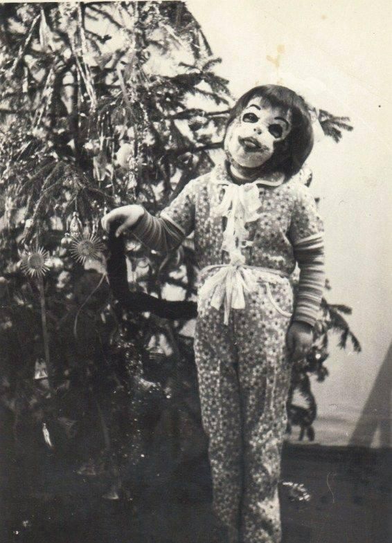 Girl in mask by Christmas tree