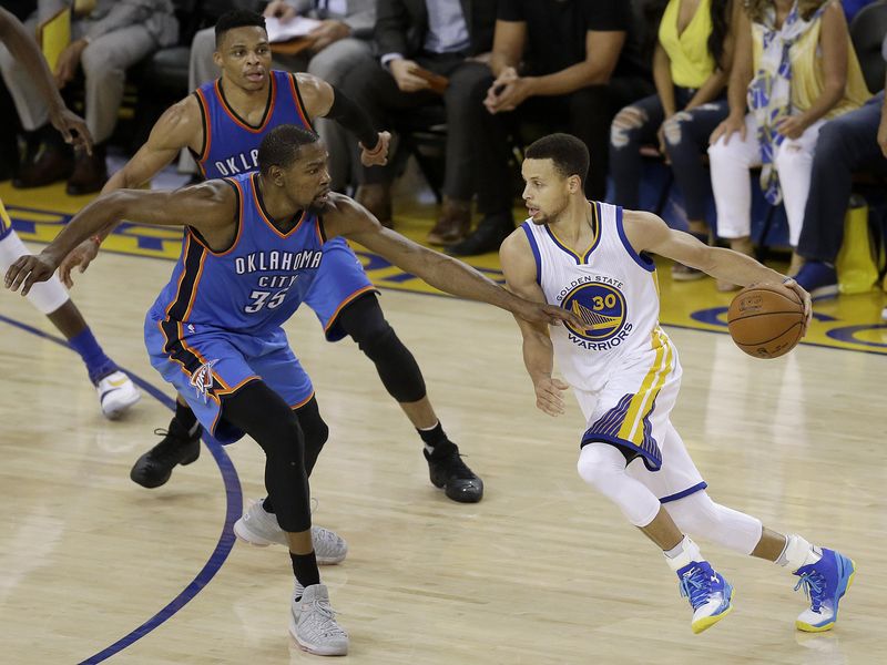 Golden State Warriors guard Stephen Curry dribbles against Oklahoma City Thunder forward Kevin Durant