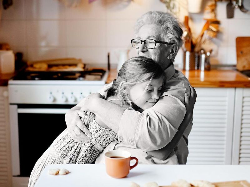 Grandmother hugging granddaughter in kitchen