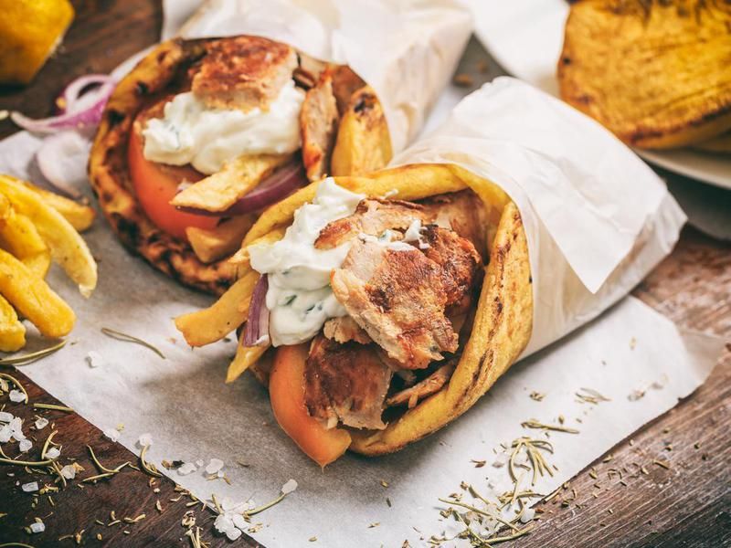 Greek gyros wrapped in a pita bread on a wooden background