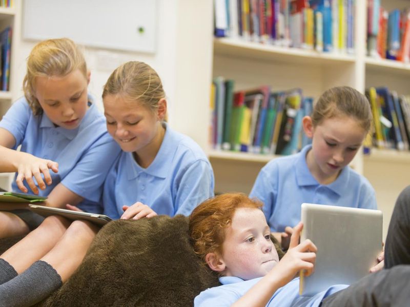 Group of school girls using tablet computers in the library