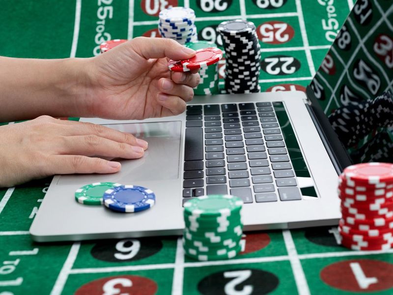 Hands typing on laptop keyboard with gambling chips