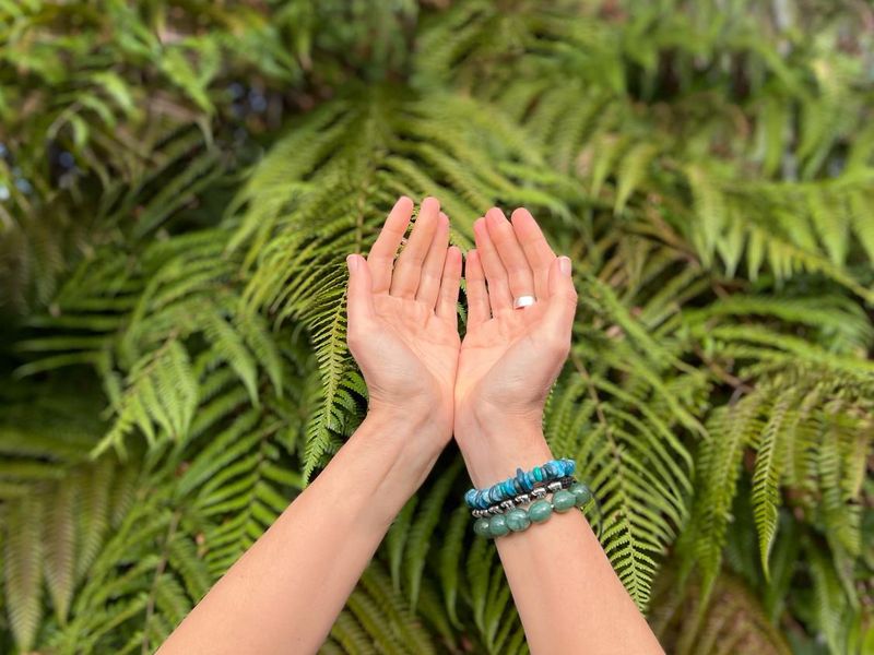 Hands with bracelets in nature with ferns