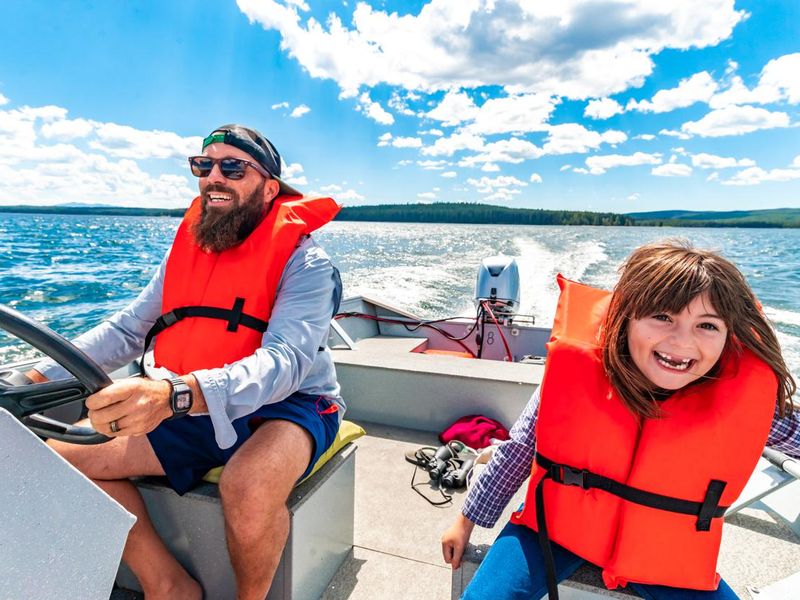 Happy father and daughter on a small motor boat on lake
