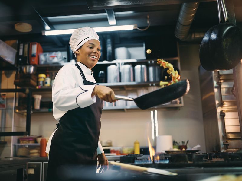 Happy female chef preparing food in a restaurant kitchen