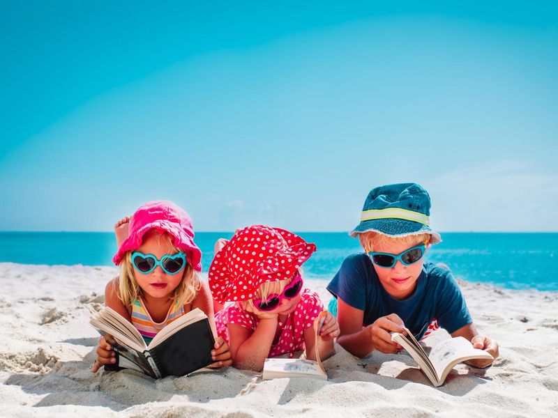 Happy kids reading books on the beach
