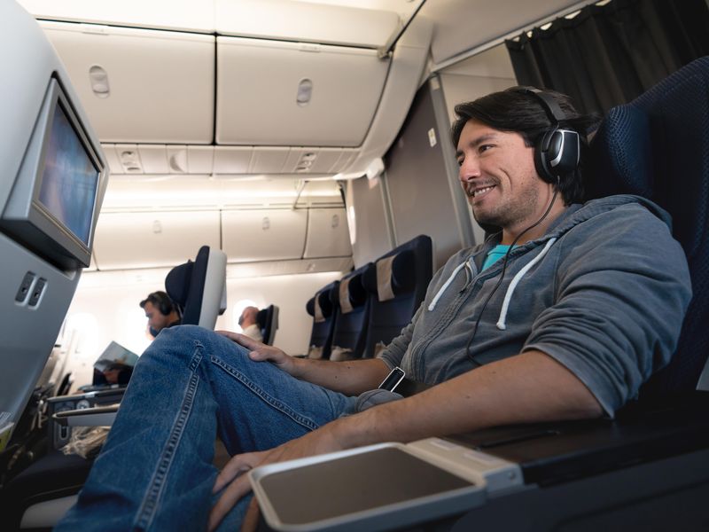 Happy man watching in-flight entertainment using headphones