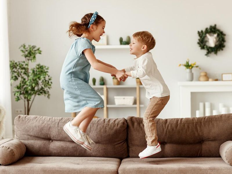 Happy siblings jumping on sofa