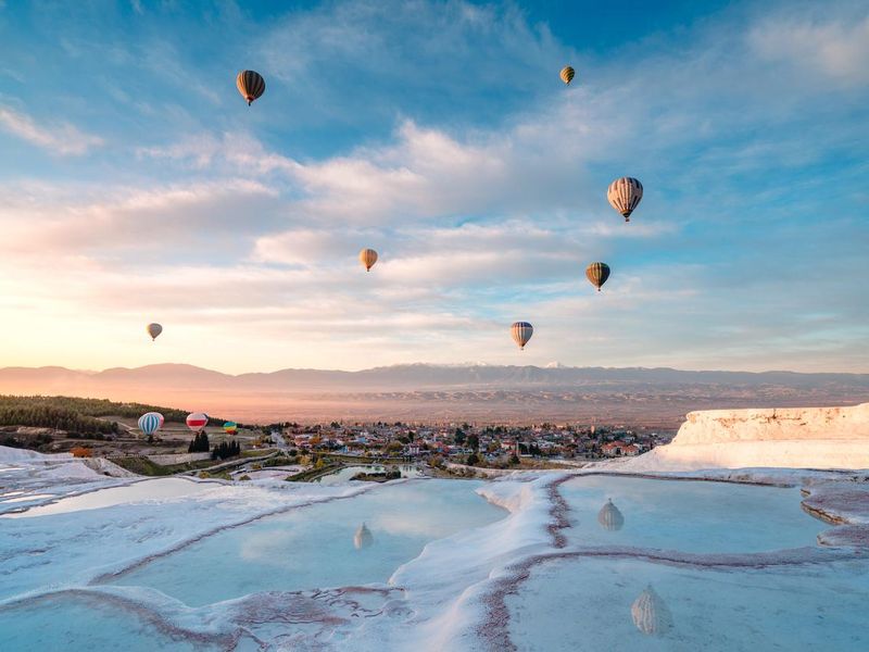 Hot air balloons in travertine pools, Turkiye