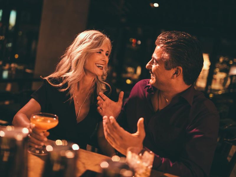 husband and wife laughing and having drinks at bar