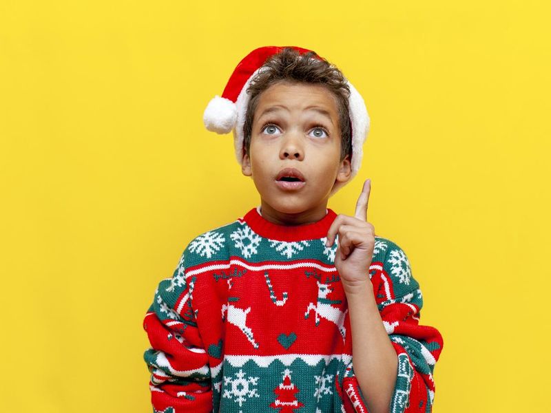 I have idea. african american boy in christmas clothes thinks and plans on yellow isolated background