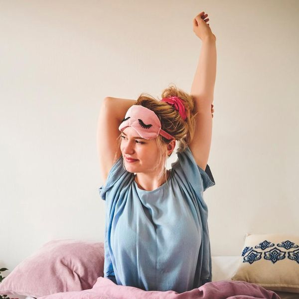 Cropped shot of an attractive young woman sitting in bed and stretching after waking up in the morning