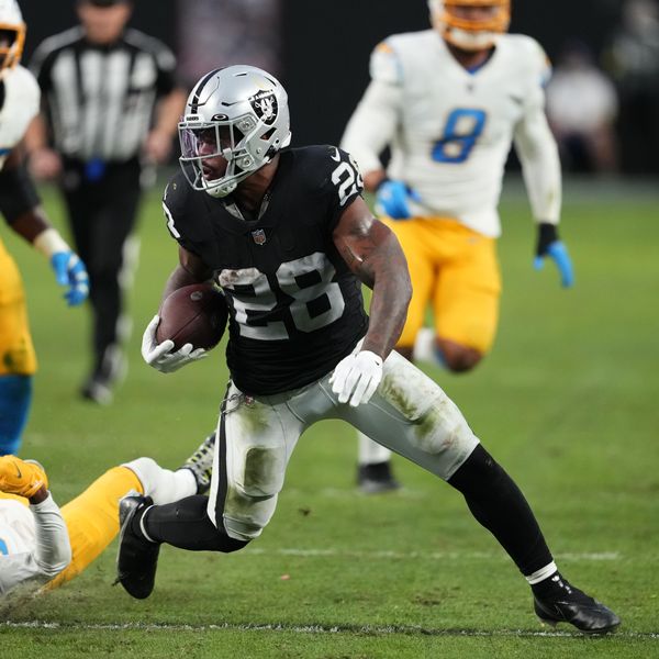Las Vegas Raiders running back Josh Jacobs (28) carries past Los Angeles Chargers safety Nasir Adderley (24) during the second half of an NFL football game, Sunday, Dec. 4, 2022, in Las Vegas. (AP Photo/Matt York)