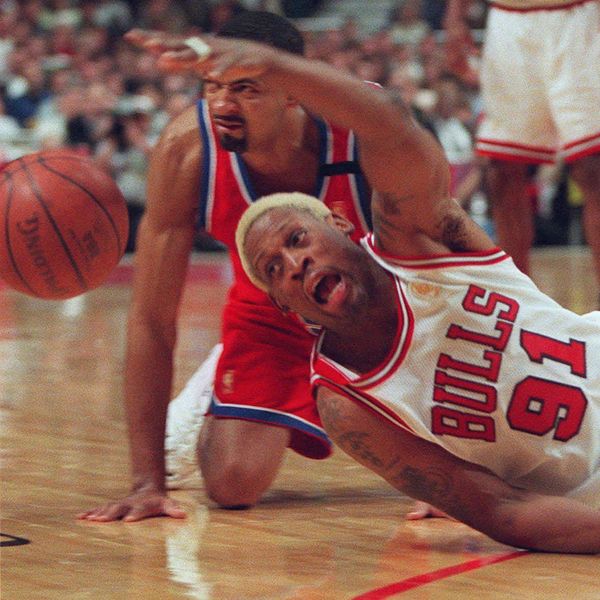 Chicago Bulls' Dennis Rodman dives for a loose ball in front of Washington Bullets' Juwan Howard during the third quarter of a first-round playoff game Friday, April 25, 1997, in Chicago. The Bulls defeated the Bullets 98-86, and Rodman was ejected in the fourth quarter of his first game back with the team after injuring his knee during the regular season. (AP Photo/Michael Conroy)