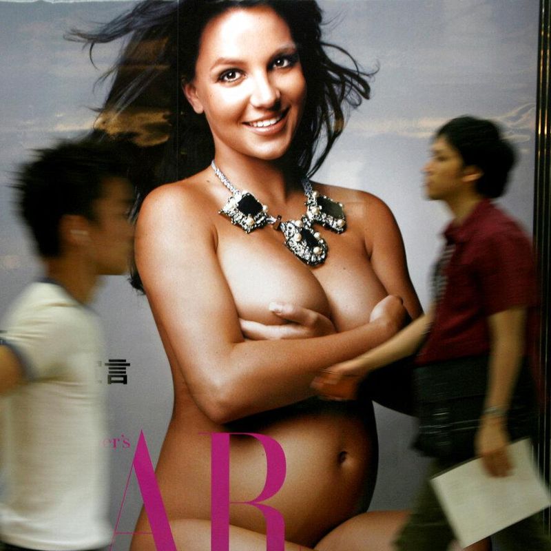 Japanese passersby walk past the poster of the recent Japanese edition of Harper's Bazaar featuring a nude and pregnant Britney Spears