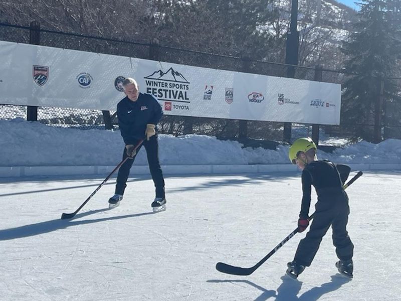 John Harrington practices hockey with young kid