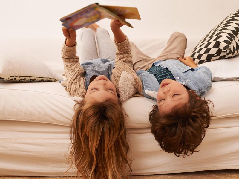 Kids laying on bed reading upside down
