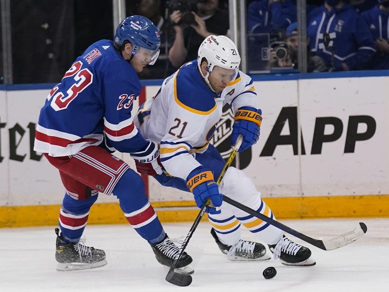 Kyle Okposo fighting for puck with Adam Fox