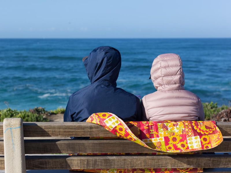 La Jolla, CA: Couple Sitting on Bench Overlooking Winter Sea
