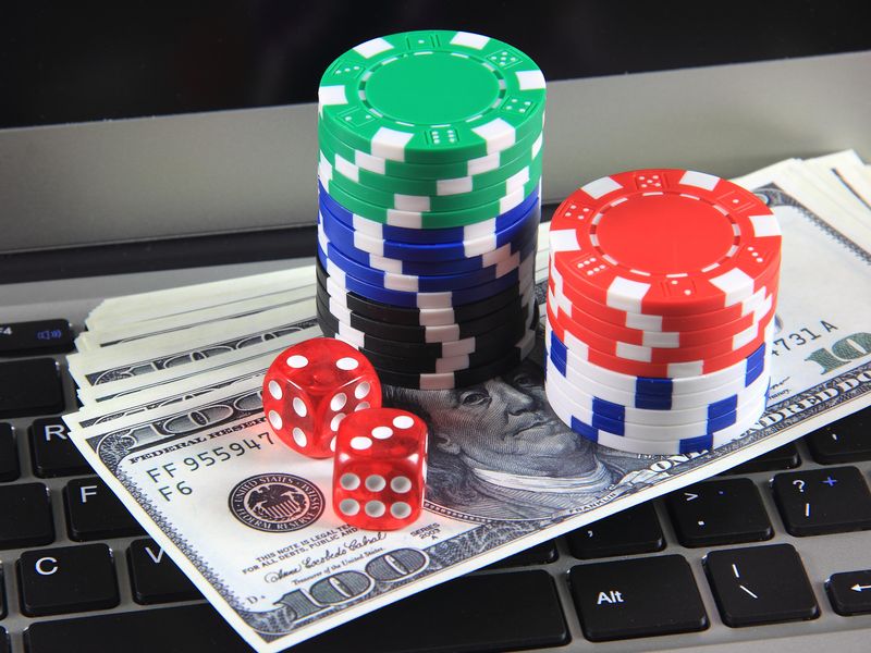 Laptop for online gambling with dice, chips and hundred dollar bills