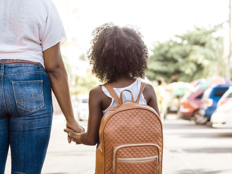 Little girl with backpack holds mom's hand