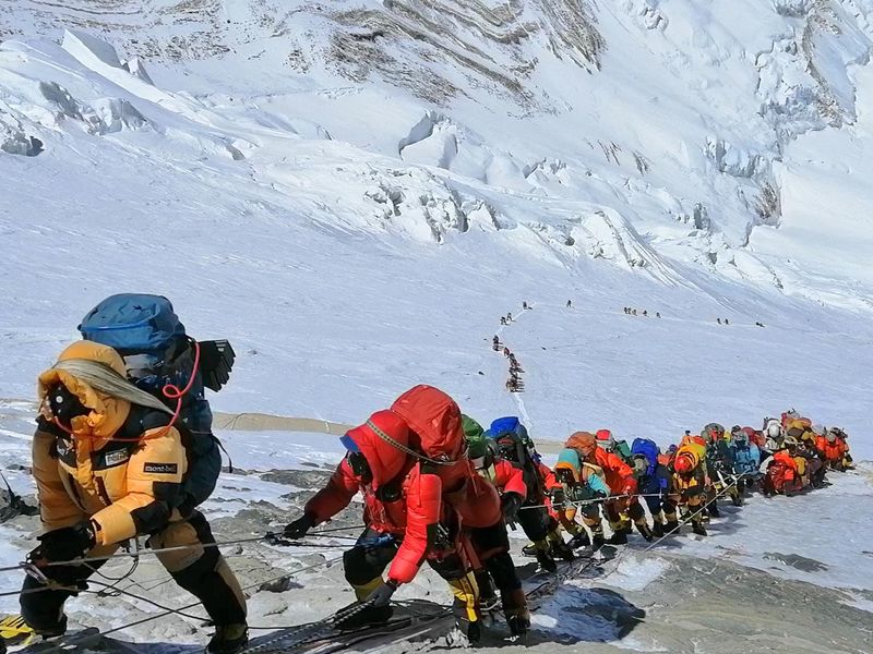Long queue of mountain climbers line path