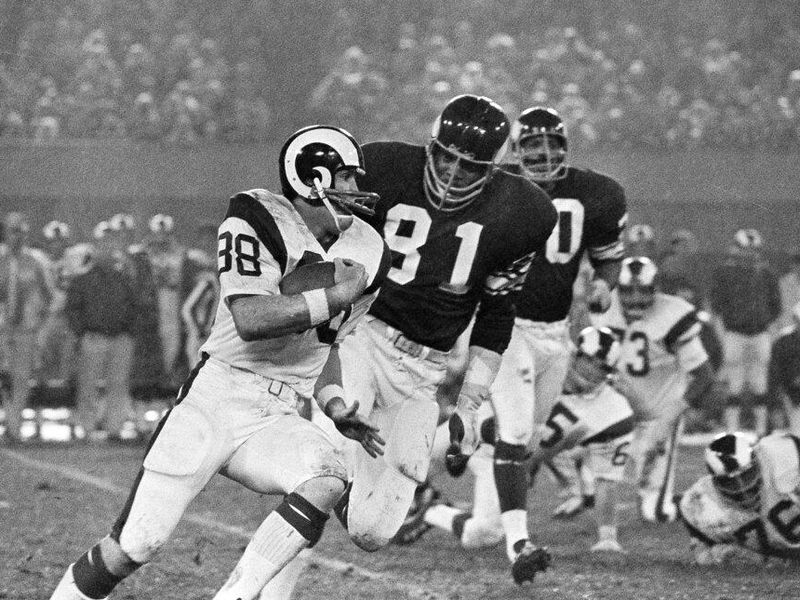Los Angeles Rams ball carrier Larry Smith (38) is chased by Minnesota Vikings Carl Eller (81)