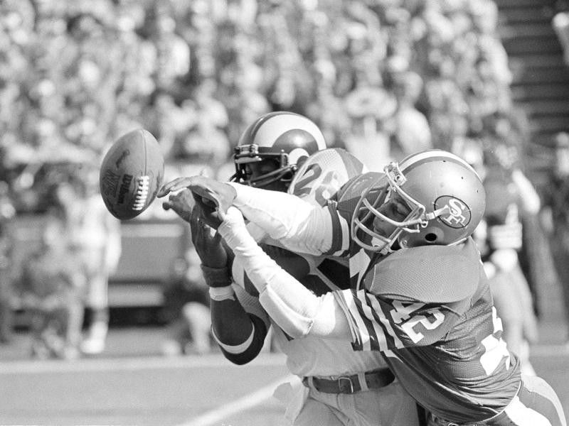 Los Angeles Rams halfback Wendell Tyler and San Francisco 49ers cornerback Ronnie Lott go for ball