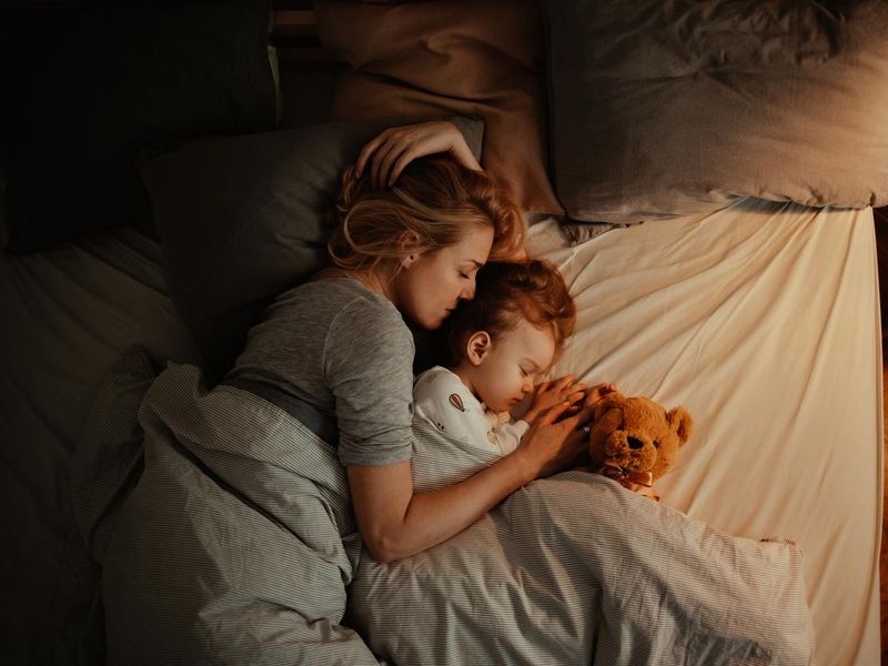 Loving mother and daughter sleeping together in bed