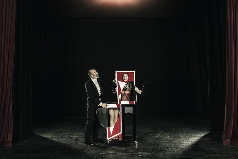 Magician performing trick with his assistant who is cut in half in the magic box