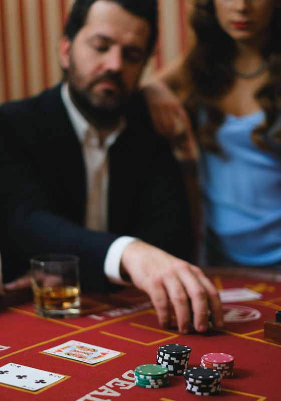 Man playing blackjack at casino with woman by his side