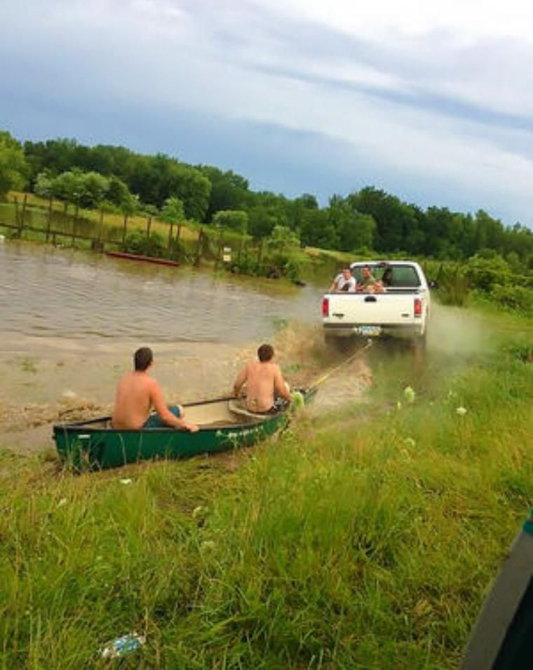 Men in a canoe getting towed by a truck