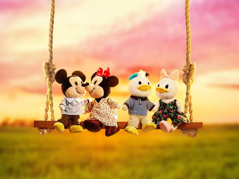 Mickey and Minnie sitting with Donald and Daisy on a swing
