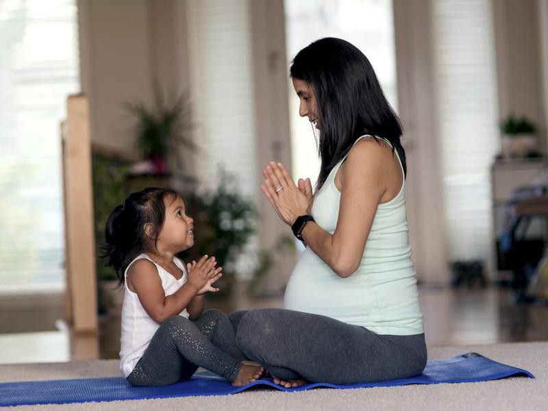 mother and daughter meditating together on yoga mat