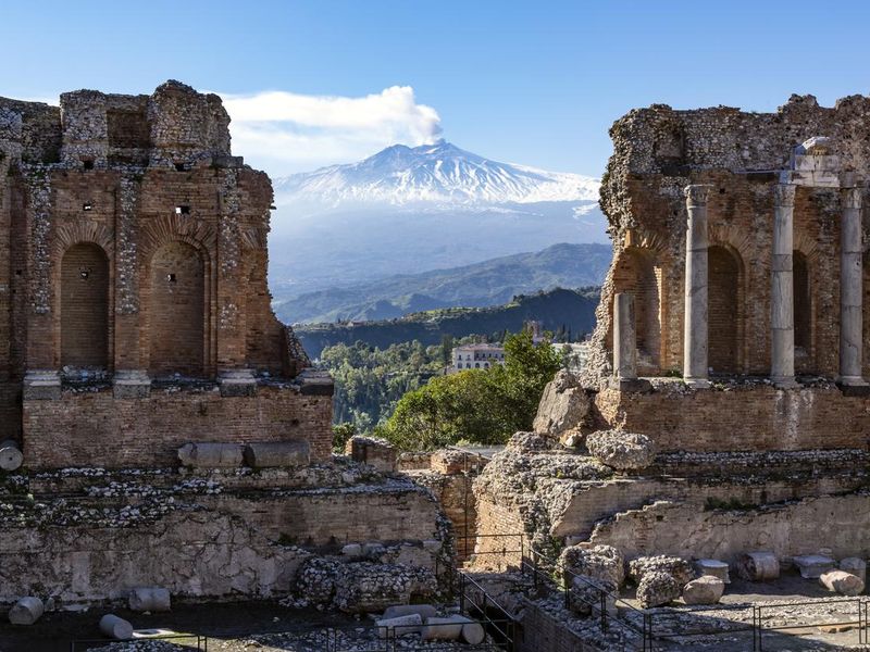 Mount Etna volcano in Sicily and ruins of ancient amphitheater in Taormina