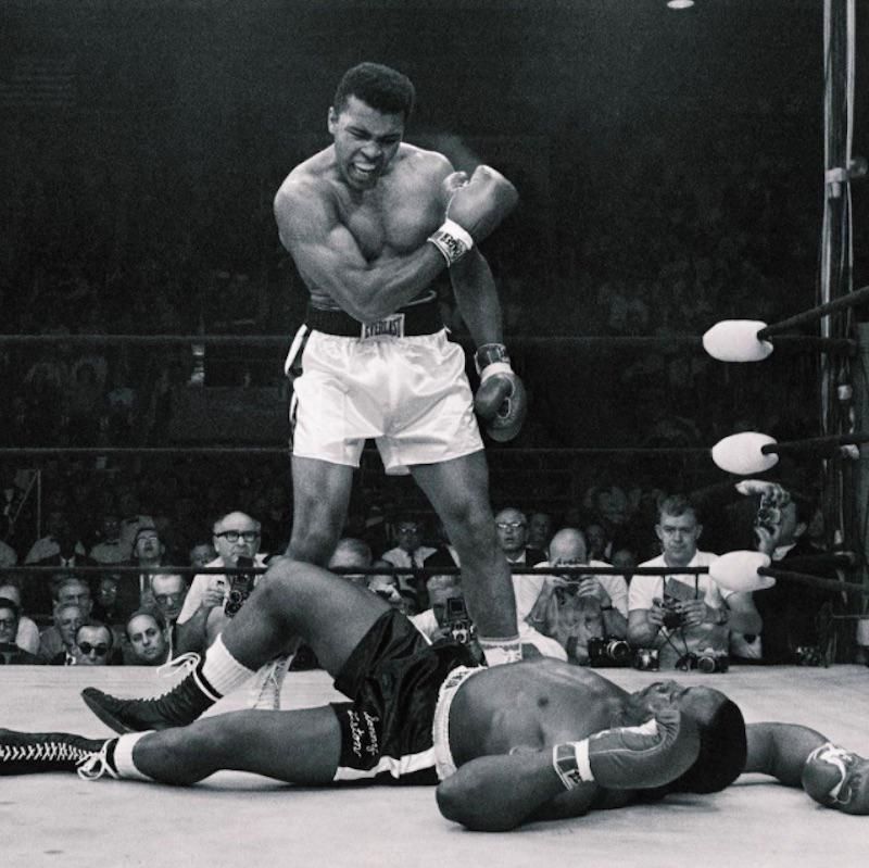 Muhammad Ali standing over Sonny Liston reacting