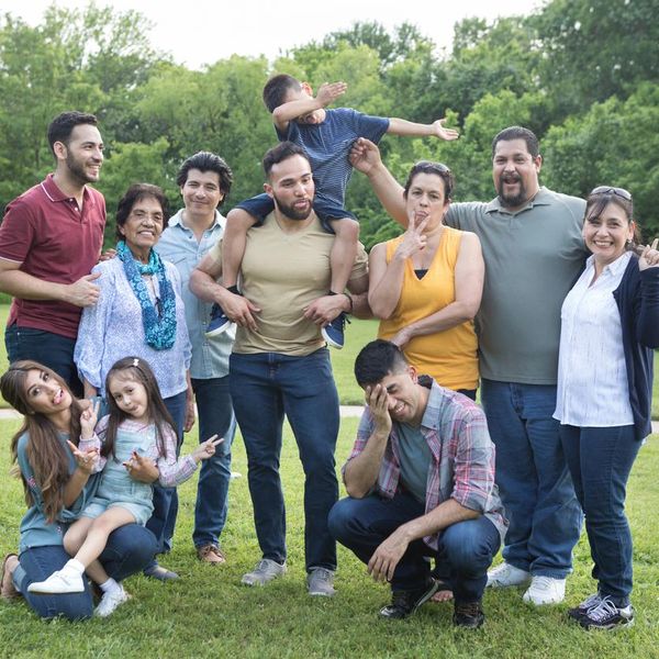 Playful family make silly faces during a group photo. They are attending a family reunion.