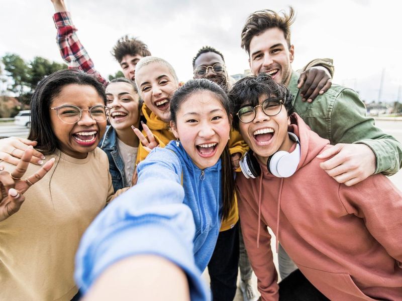 Multiracial friends taking big group selfie shot smiling at camera -Laughing young people standing outdoor and having fun - Cheerful students portrait outside school - Human resources concept