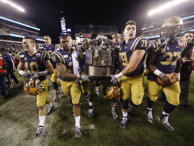 Navy midshipmen carrie off the Commander in Chief's trophy after defeating Army