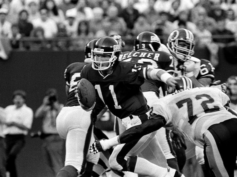 New York Giants quarterback Phil Simms tries to get away from Washington Redskins Dexter Manley
