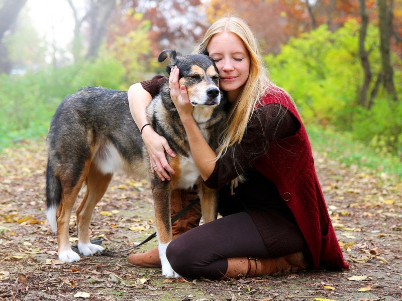 Peaceful, happy woman hugging old German shepherd dog lovingly