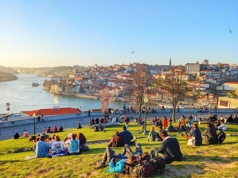 People enjoying the sunset on a grassy hill in Porto